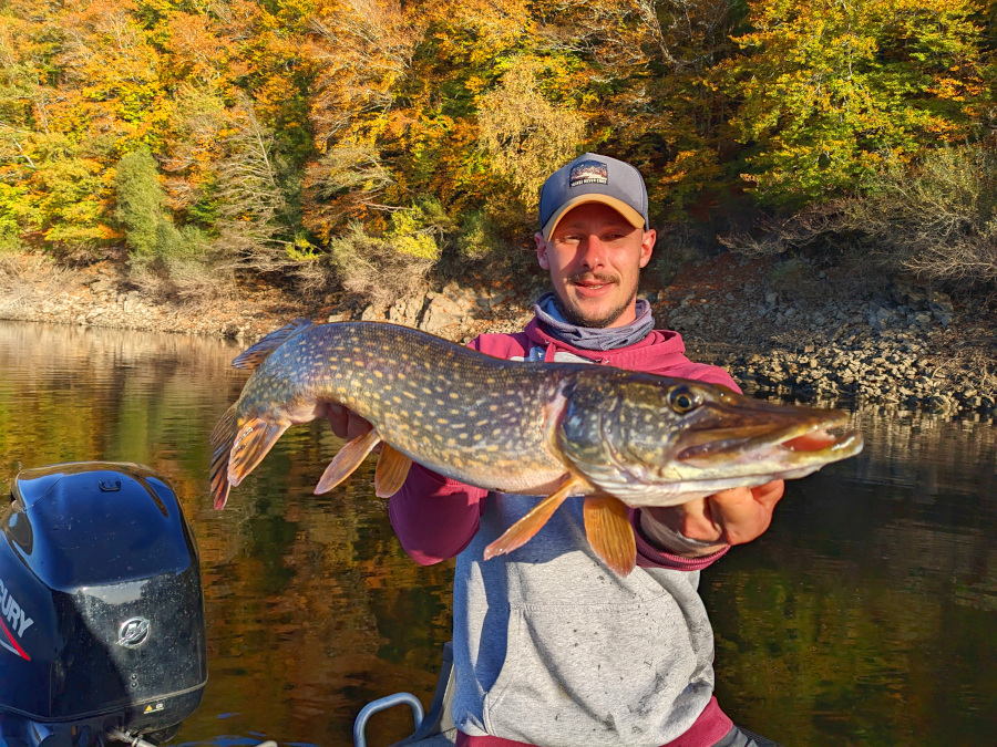 photo d'un pêcheur avec un beau brochet dans les bras qu'il vient de capturer en bateau