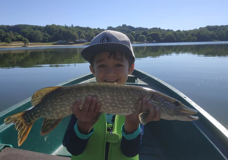 photo d'un enfant ayant capturé un brochet en bateau